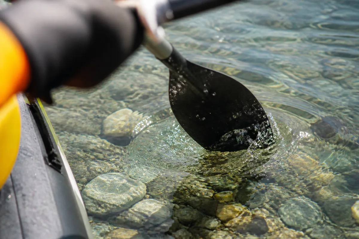 Pagaie en gros plan effleurant l’eau claire et transparente d’une rivière