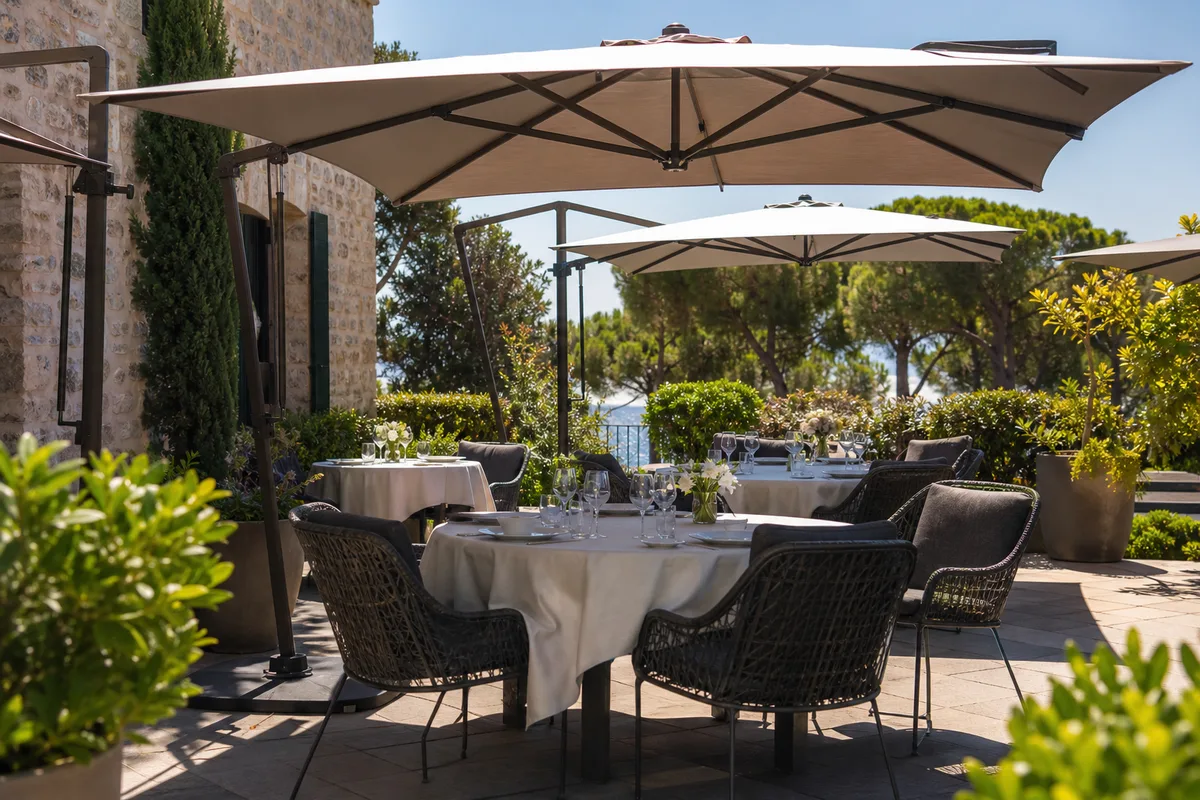 Terrasse de restaurant ombragée avec chaises confortables et tables dressées prêtes pour le service